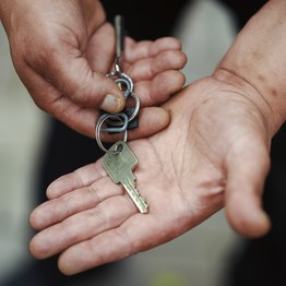 Ein Mann hält einen Haustürschlüssel in den Händen