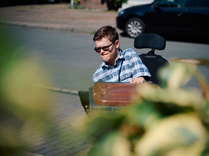 Ein Mann, der einen Rollstuhl benutzt, stellt eine Mülltonne an die Straße (vergrößerte Bildansicht wird geöffnet)