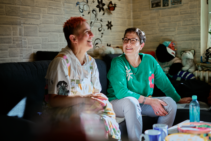 Susanne Marquardt und Nadine Noack sitzen auf dem Sofa und lachen