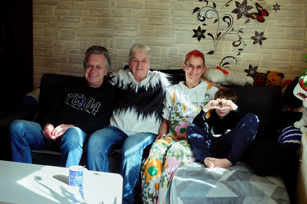 Eine Familie sitzt entspannt gemeinsam auf dem Sofa