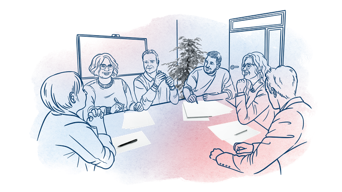 Mehrere Menschen sitzen um einen Konferenztisch und besprechen etwas
