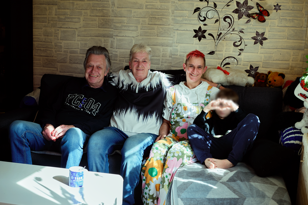 Eine Familie sitzt entspannt gemeinsam auf dem Sofa