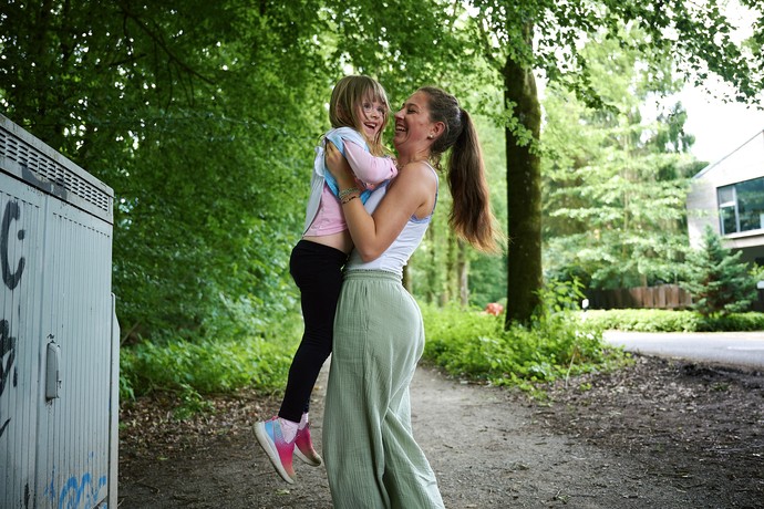 Eine junge Frau fängt eine springendes Kind auf.